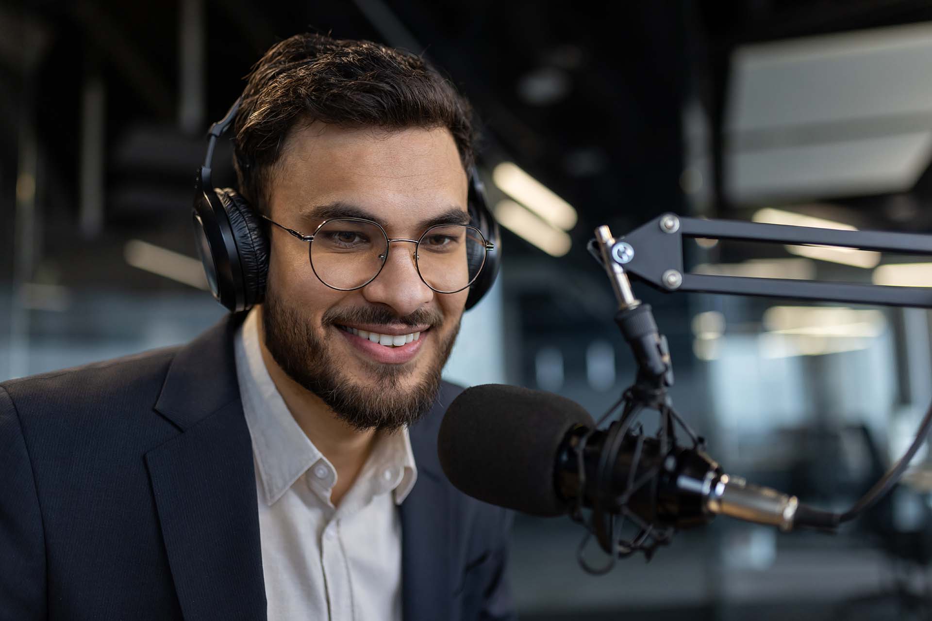 Close-up of a man recording a video online training course podcast. Businessman in business clothes using a professional microphone and headphones